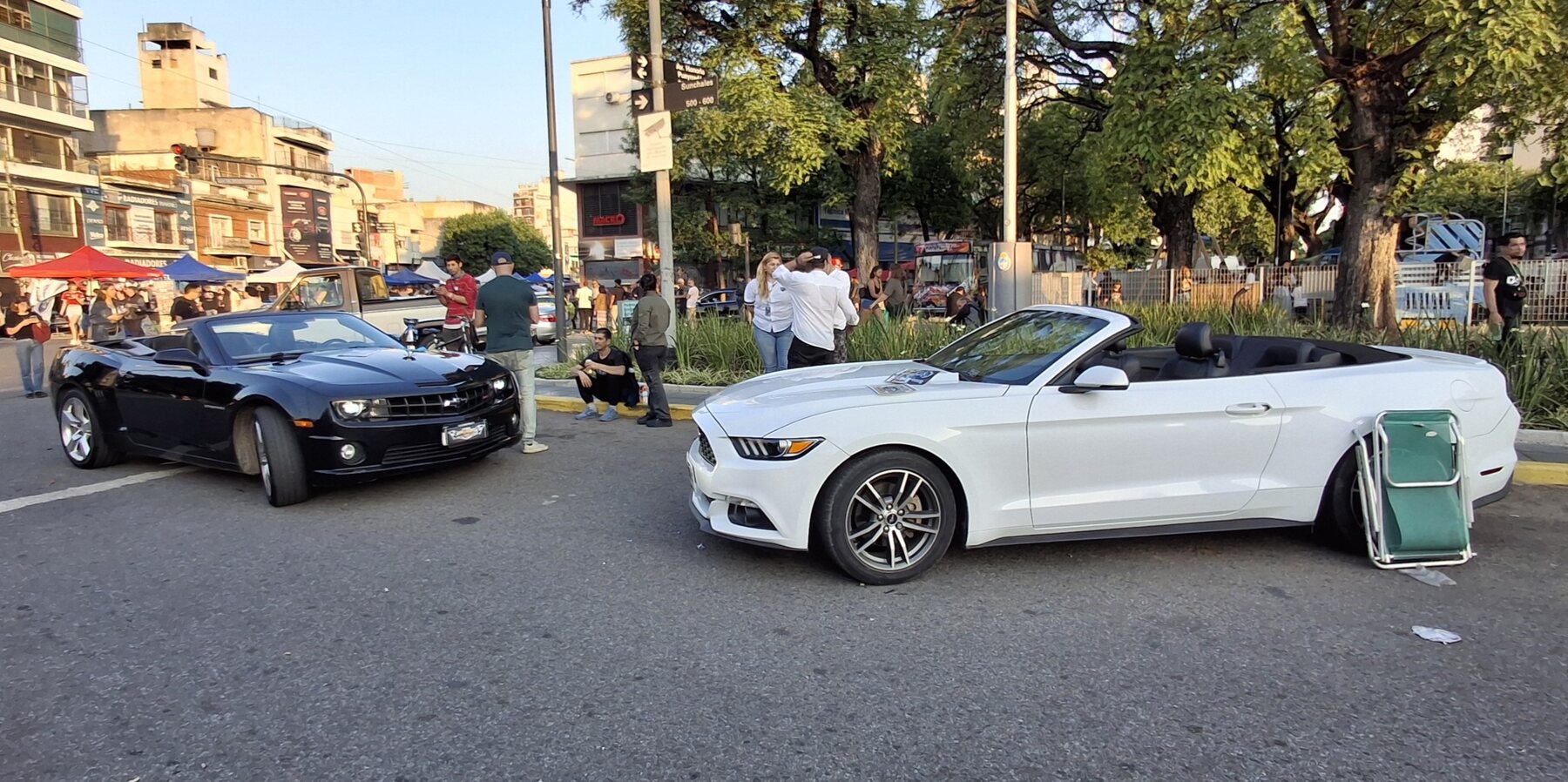 Dos Ford Mustang convertibles sobre la avenida en la Expo Warnes 2025.
